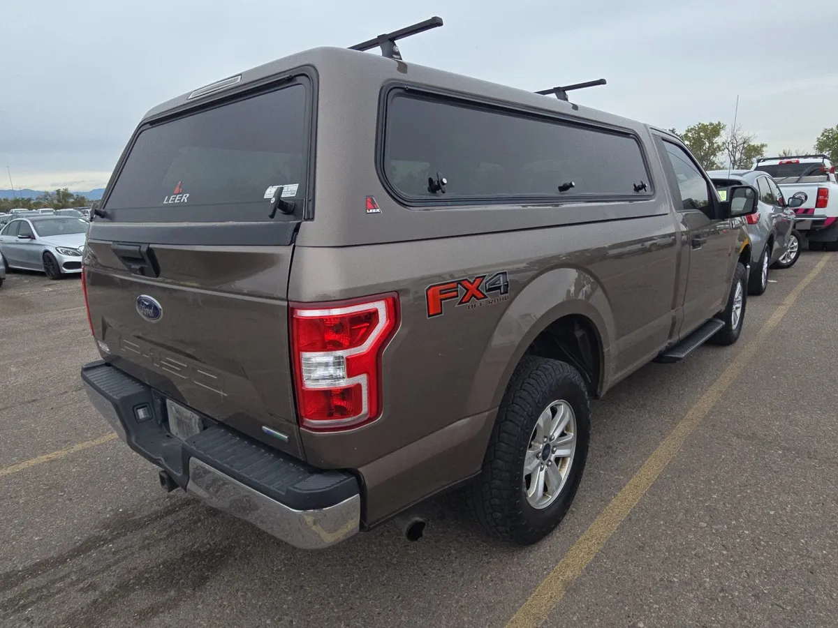 Rear three-quarter view of the 2018 Ford F-150 XLT showing the FX4 Off Road badge on the bedside and the camper shell