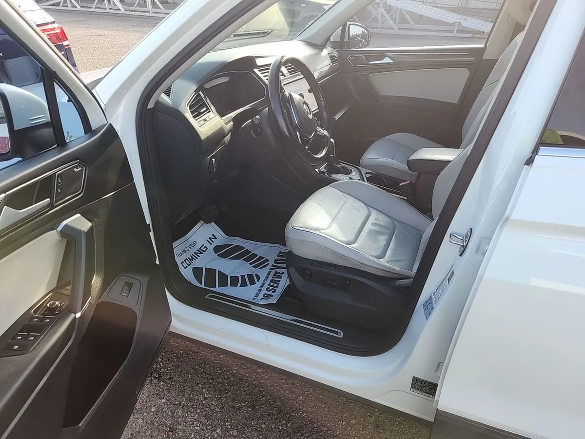 Interior of the 2018 Volkswagen Tiguan SEL Premium with light gray leather seats and a paper floor mat from the auction
