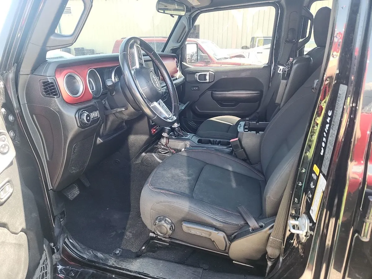 Interior of the 2020 Jeep Wrangler Unlimited Rubicon with black cloth seats and red dash accents