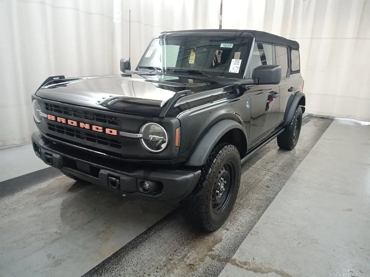 2023 Ford Bronco Black Diamond four-door in black with a soft top, orange Bronco grille lettering and black steel wheels, front three-quarter view in the auction photo booth