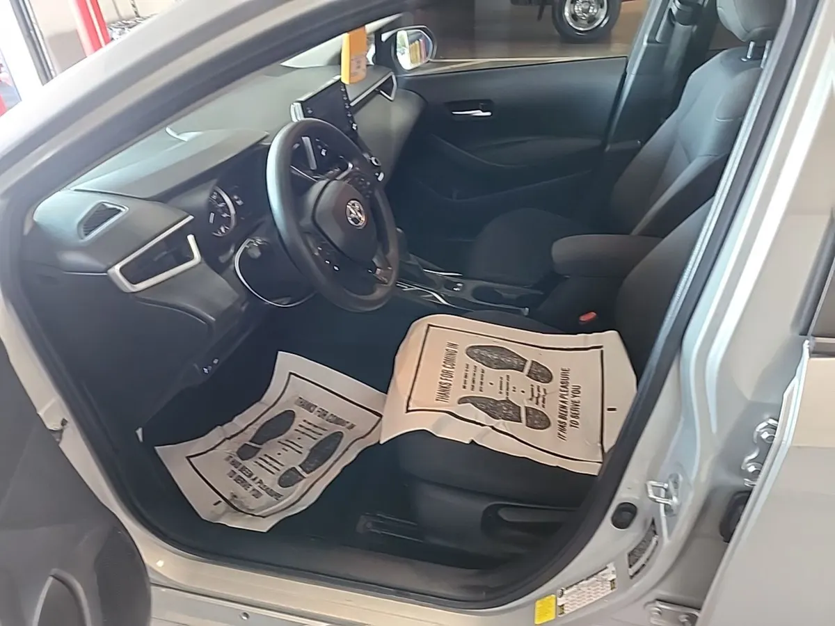 Interior of the 2021 Toyota Corolla LE with black cloth seats and paper floor mats from the auction