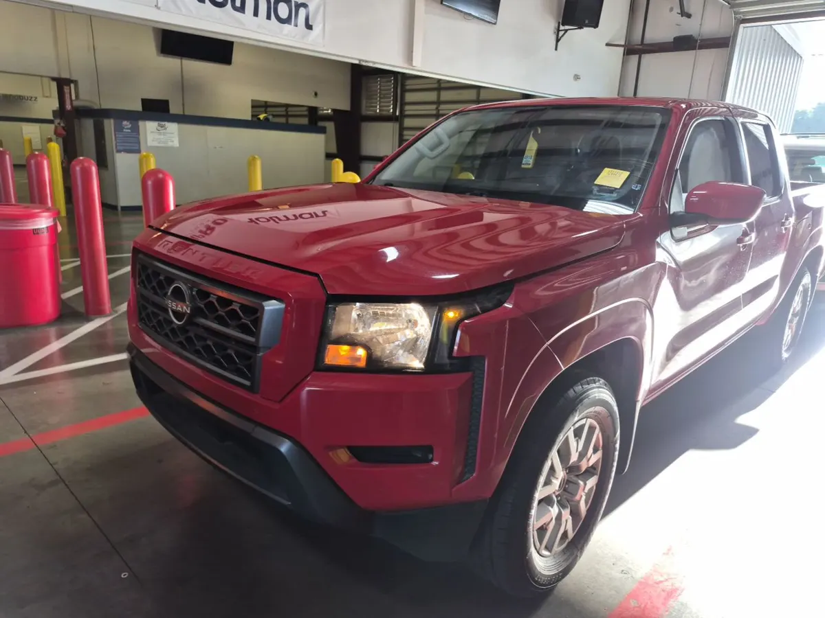 2022 Nissan Frontier SV crew cab in red, front three-quarter view inside the auction building