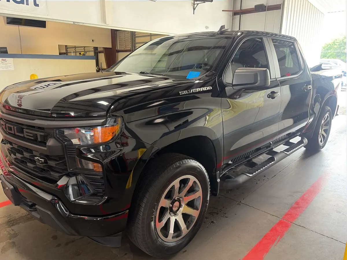 2022 Chevrolet Silverado 1500 Custom crew cab in black with running boards, front three-quarter view inside the auction building