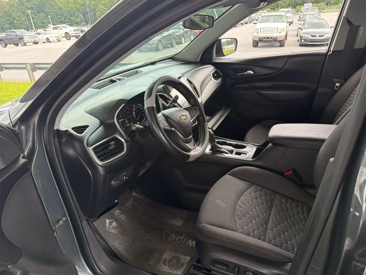 Interior of the 2018 Chevrolet Equinox LT showing black cloth seats, dash, and steering wheel with an aftermarket cover