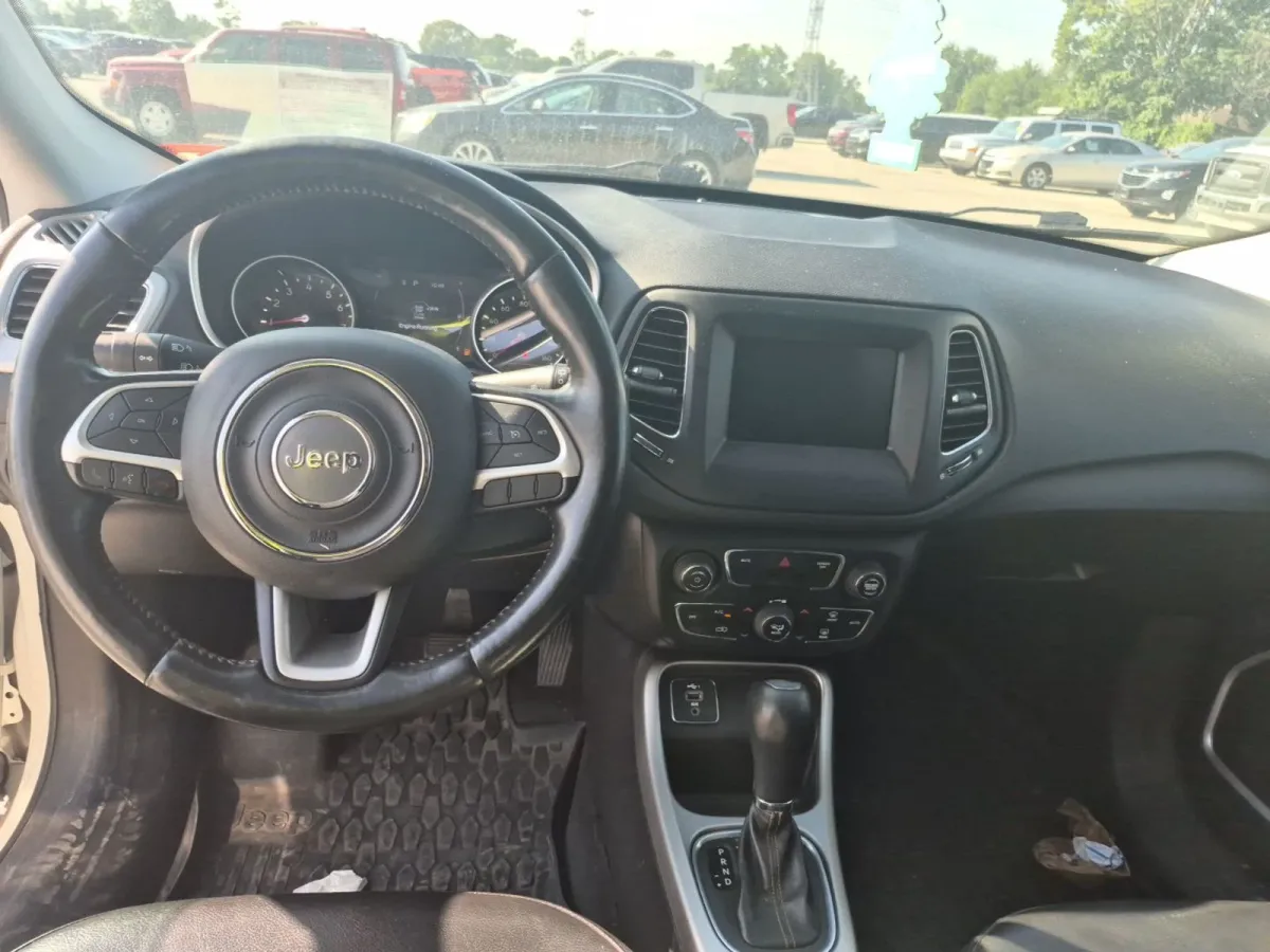 Interior of the 2020 Jeep Compass Latitude showing the dash, a worn steering wheel wrap, and Jeep floor mats