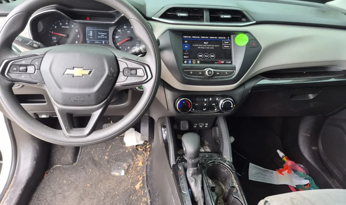 Interior of the 2021 Chevrolet Trailblazer LT showing the dash and touchscreen, with debris on the floor and a dirty center console